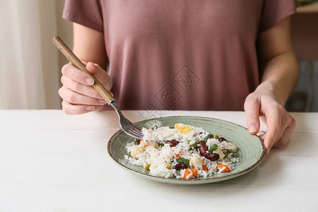 妇女在桌边吃着豆子和蔬图片