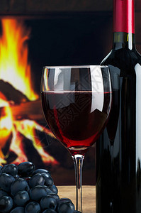 酒杯和酒瓶在火炉燃烧的火场背景下黑暗的照片图片
