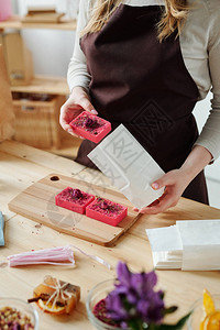 将手工制作的粉红色肥皂棒用在车间木制桌子上的白色纸图片