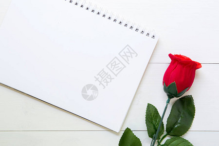在木桌上用红玫瑰花和笔记本赠送礼物图片