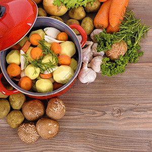 含有机蔬菜和草药的红锅放在木制桌上图片