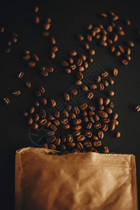 咖啡豆从黑色背景的纸包中散落平躺新鲜芳香烤咖啡豆顶视图咖啡店概念黑暗喜图片