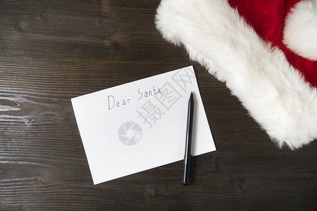写给圣诞老人的信是木制背景空信笔和帽子圣诞节图片