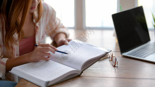 在舒适的起居室木桌上看一眼聪明的大学生女孩图片