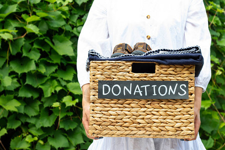 女手拿着一个绿色背景上的捐赠衣物盒慈善和捐赠理图片