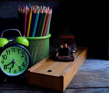 木制学校铅笔盒闹钟彩色铅笔旧木桌上图片