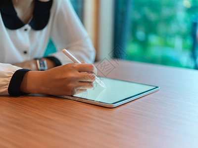 在研讨室的桌子上使用带有手写笔的模拟数字平板电脑近距图片