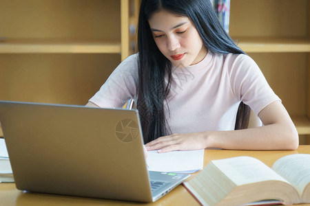 年轻的亚洲女学生在图书馆学习和做笔记图片