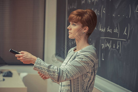 微笑的女老师大学里的年轻女教师大学课堂教学黑板上用粉笔描述数据背景图片