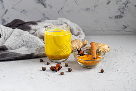带有香料的金色牛奶姜黄丁香黑胡椒和一滴植物油传统的印度饮料在浅色背景上健康饮图片
