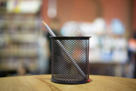 银铅笔放在室内桌子上的黑网状材料的纸笔和铅笔的组织者中图片