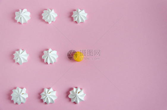 蛋白酥皮白色的空气蛋白酥皮在粉红色的背景上排成一排有节奏的图案和一个黄色的马卡龙在蛋白酥图片