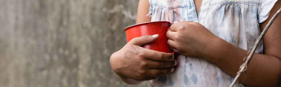 贫困的非裔美国儿童在城市街道上拿着金属杯背景图片