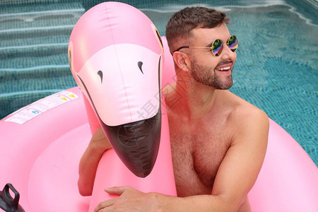 英俊年轻男子的近视肖像在游泳池里用粉红图片