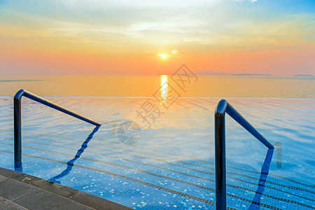 带楼梯的游泳池和黄昏时分在海上欣赏壮观的热带日落全景图片