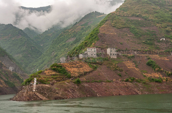 长江西岭峡谷灰色的房子建在绿色的水面上下降的云景下图片