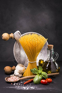 与要煮熟的意大利产品未煮过的意大利面番茄和新鲜罗勒图片
