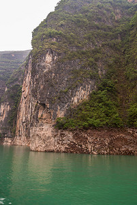 大宁河上的大雾或迷雾峡谷棕色的岩石峭壁像墙壁一样沿着峡谷下降到翡翠绿的水中一些绿色的树叶和黑图片