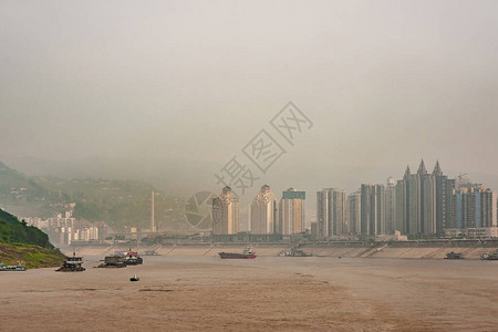 长江在几艘船上的棕色水岸上有高楼的城市景观雾和背景图片