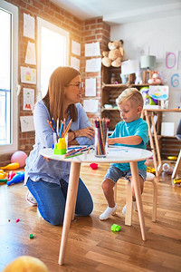 年轻的白种人孩子和老师在幼儿园玩耍母子在游戏室图片