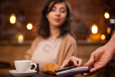 有魅力的女人在咖啡店使用无线支付手机支付的照片美丽的女人使用无线技术在咖背景图片