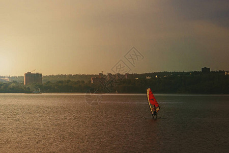 在城市里做运动帆板运动橙色风帆下的人在水面上移动背景是图片