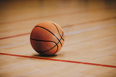木制球场地板上的经典篮球与背景中的模糊竞技场密切相关硬木篮球图片