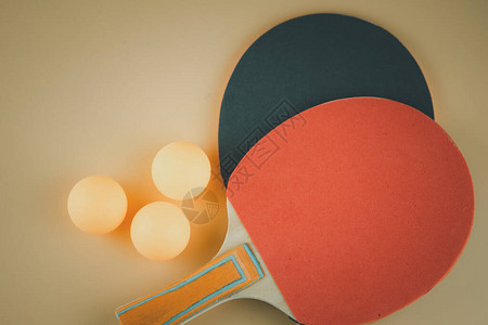 橙色背景中的两个乒乓球或乒乓球拍和球图片