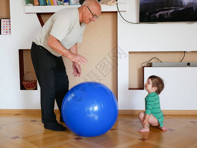 孩子和祖父玩球在家里打一个大蓝球一个男孩正在和图片