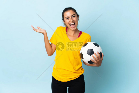 年青的西班牙裔足球运动员女在蓝色背景与世隔绝图片