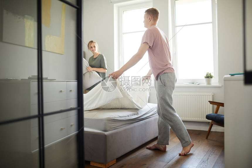 穿着运动裤和T恤衫的年轻男子睡觉后早上在帮助妻图片
