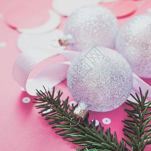 新年圣诞假期庆祝作文珍珠装饰玩具球绿色冷杉树枝闪耀五彩纸屑粉红色纸背景复制空间用于问候明信片文字设背景图片