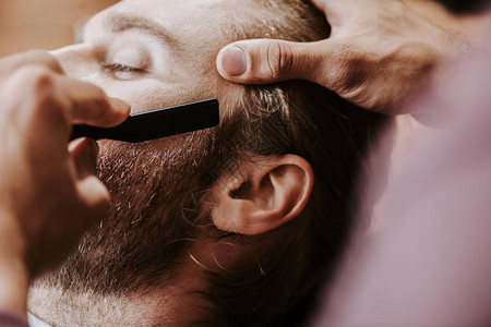 理发师用剃须刀剃胡子的人裁剪视图图片