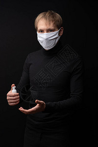 戴医疗面具的男人展示了如何用抗消毒剂治疗他的双手科背景图片