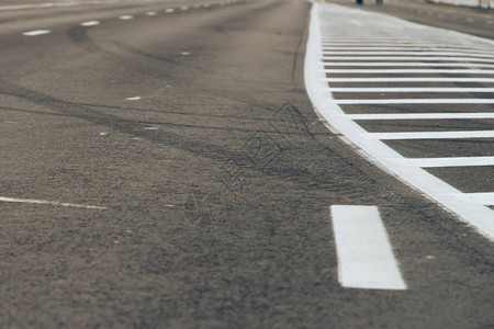 特写道路的前景轨道上的沥青分隔条上有两条白色条纹道路图片