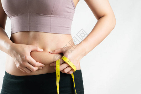 肥胖的女人手握着过多的腹部脂肪图片