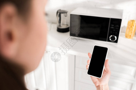 厨房微波附近妇女使用智能手机的切图片
