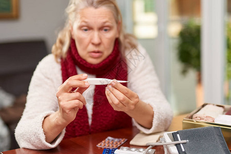 女人看着温度计拿着数字温度计的女手发烧烟道或的概念图片