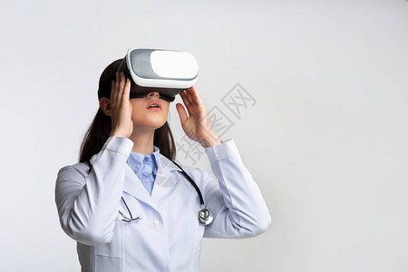 使用虚拟现实头盔进行白工作室背景医学诊断的女医生图片