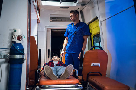 躺在救护车里的担架上一个提供急救的护理人员她被送去医院图片