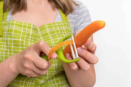 女人用食物削皮器削胡萝卜背景图片