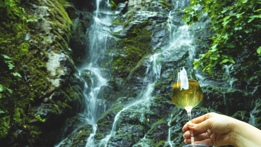 女手握着一杯白葡萄酒在背景岩山和图片