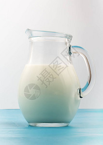 白色背景上装满新鲜白牛奶的玻璃壶图片