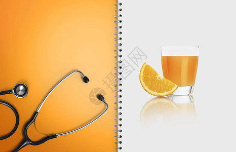 平衡医疗饮食与健康食品的概念带听诊器的纸质笔记本页面和白色隔离的橙汁图片