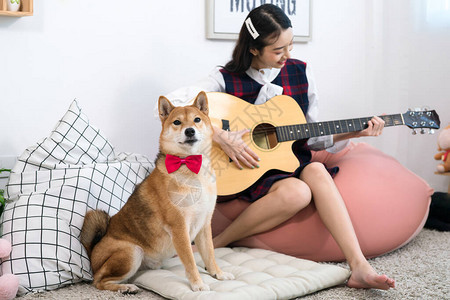 女孩在白色的起居室里和ShibaInu图片