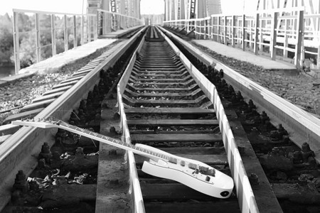 铁路和工业灰色铁轨上的黑白电吉他图片