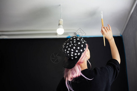 穿黑色帽子和毛衣的年轻女孩背着粉色头发刷子和白颜色的壁画图片