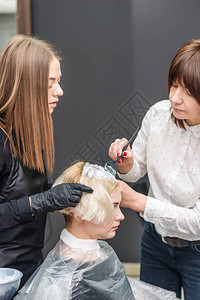 专业理发师用刷子把白染色涂在头发图片