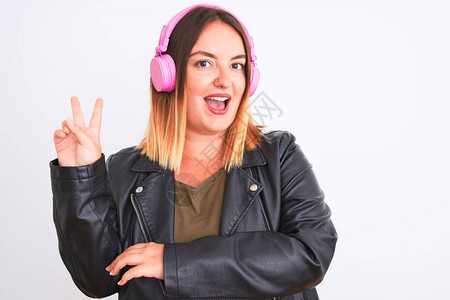 年轻漂亮的女人在孤立的白色背景上用耳机听音乐图片