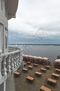 靠近海湾的户外餐厅里的空木桌和白船图片